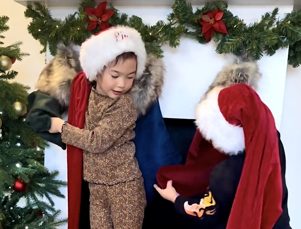 to børn i nissekostumer hygger sig med nisseleg foran en pejs fyldt med decemberhygge